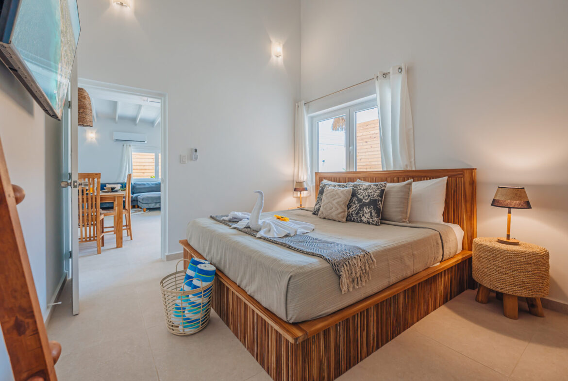 Bedroom with wood-slat bed frame and view into the living area, Seaside Modern Villa, Aruba