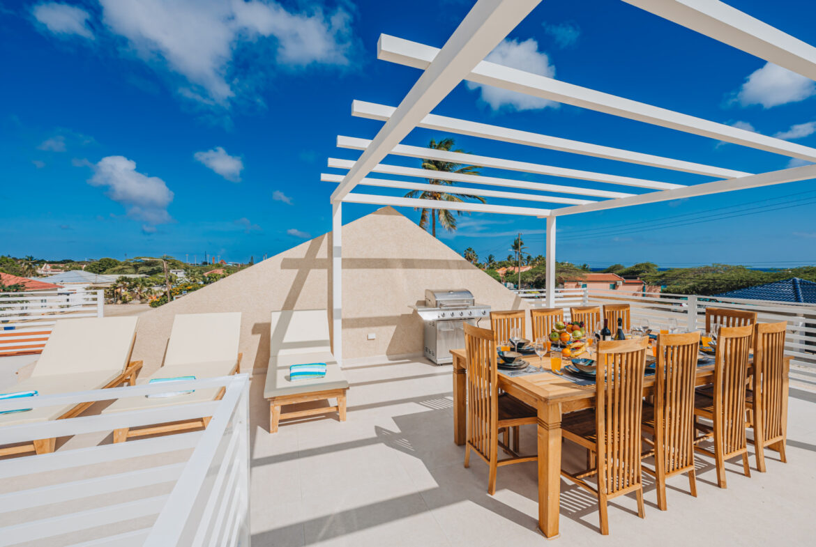 Rooftop terrace with pergola-covered dining table for eight, lounge chairs, and ocean view, Seaside Modern Villa, Aruba