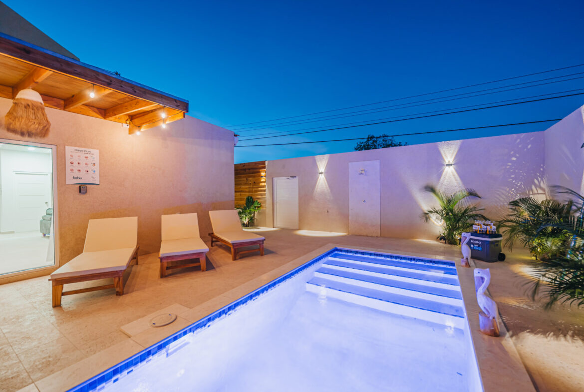 Blue-lit pool at twilight with lounge chairs beside the studio, Seaside Modern Villa, Aruba