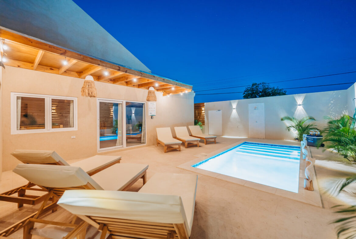 Poolside patio at twilight with string lights and lounge chairs, Seaside Modern Villa, Aruba