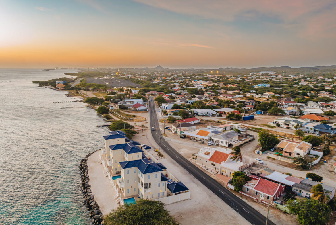 Aerial drone view of the coastal neighborhood and villa row at sunset, Aruba