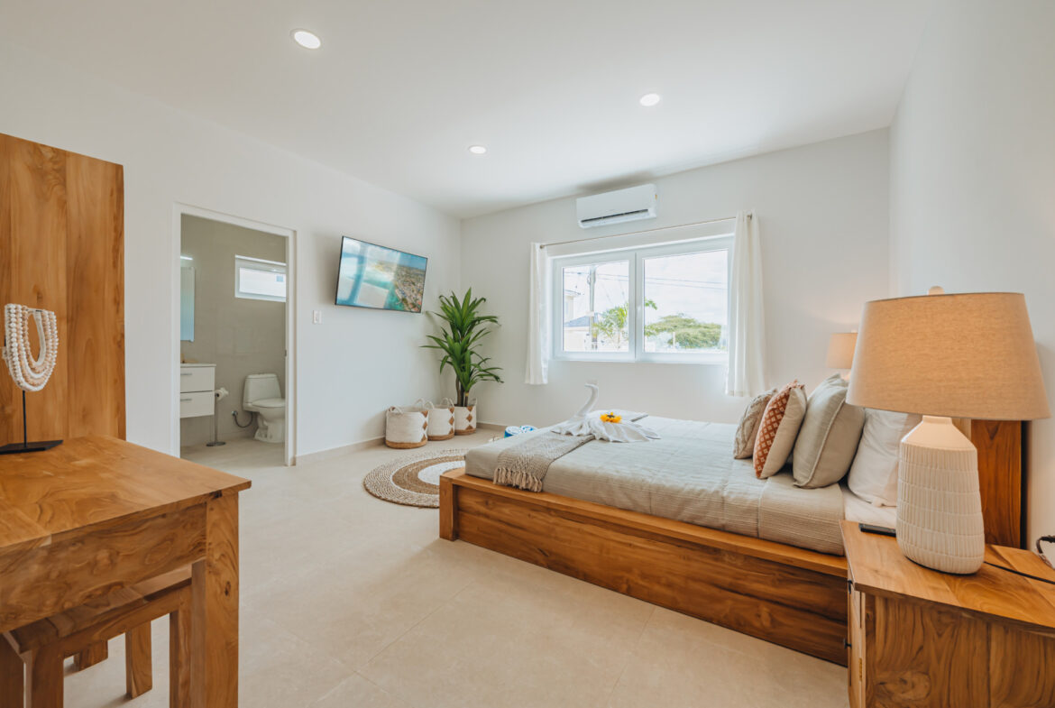 Bedroom with wardrobe, wall-mounted TV, and en-suite bathroom visible through doorway, Seaside Modern Villa, Aruba