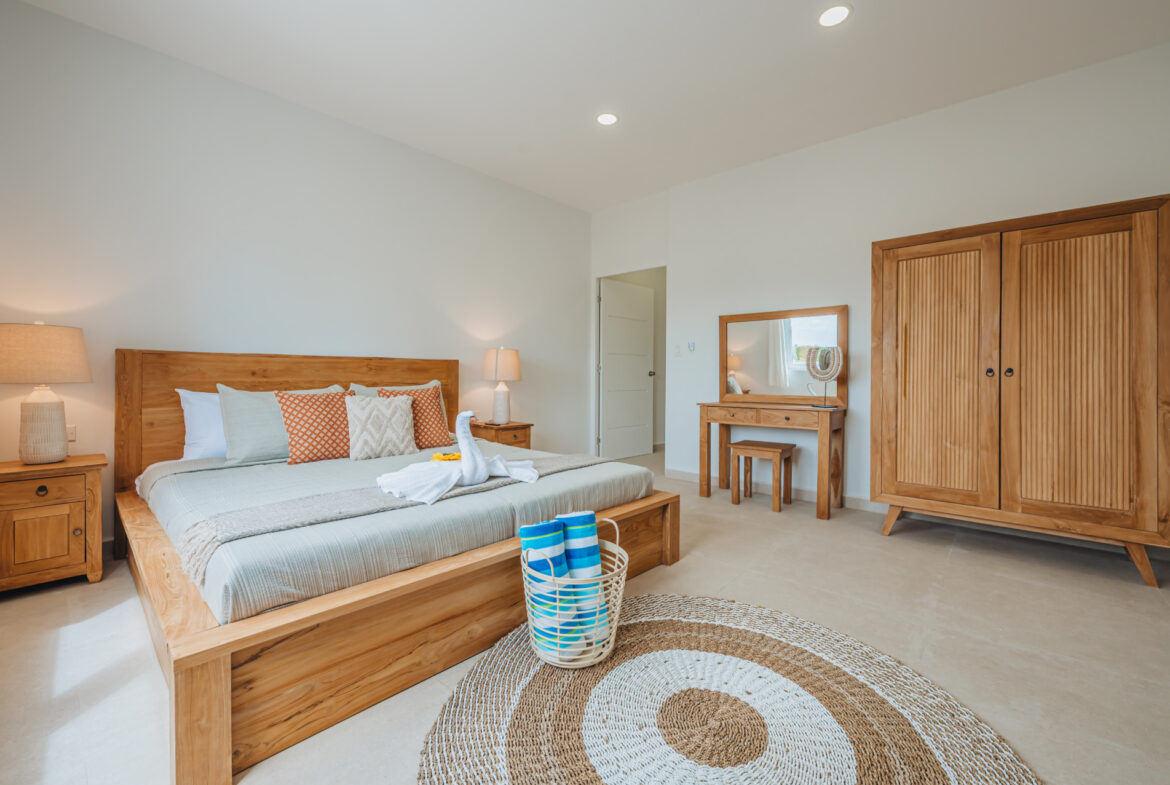 Bedroom with king bed, wood wardrobe, vanity desk, and round woven rug, Seaside Modern Villa, Aruba