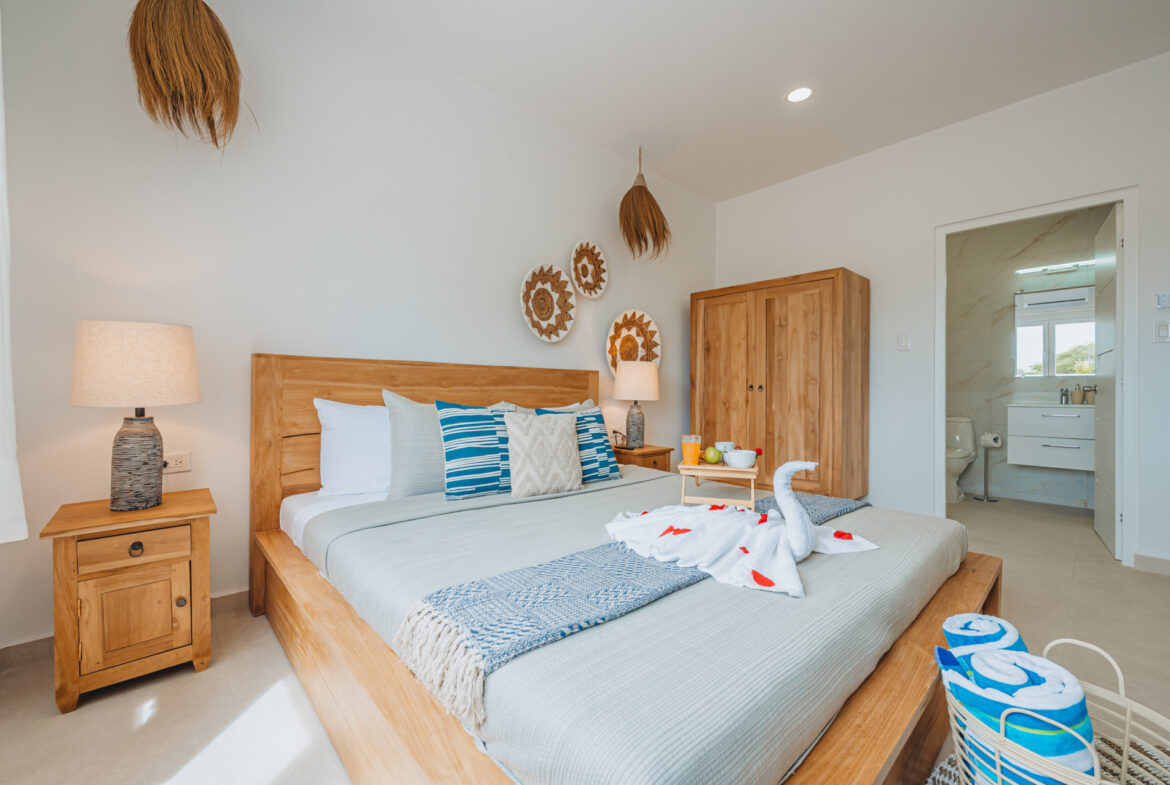 Bedroom with king bed, decorative towel swan, and en-suite bathroom, Seaside Modern Villa, Aruba