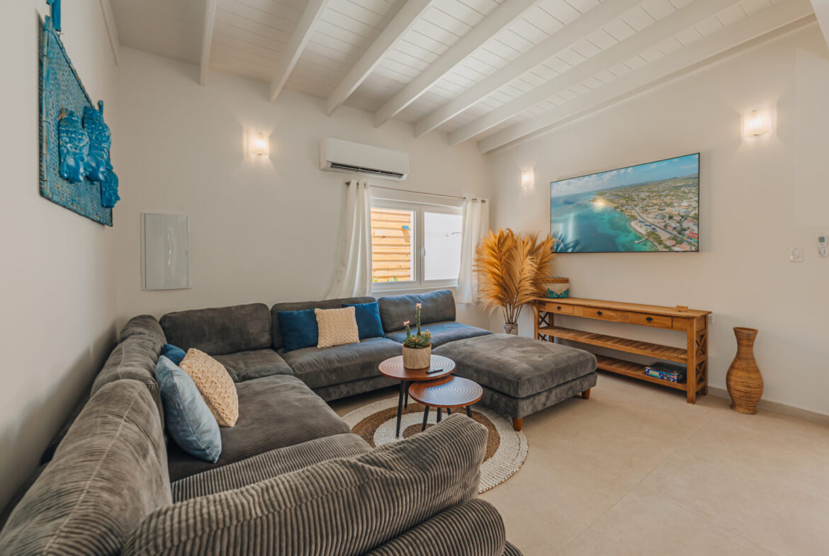 Living room with L-shaped sofa, wall-mounted TV, and wood console table, Seaside Modern Villa, Aruba